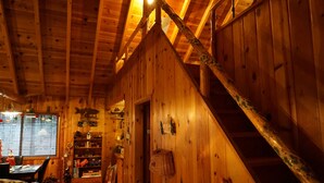 A cozy cabin interior with wooden walls, a staircase, and a dining area with a table and chairs. - Family Cabin in the Pines. All Wood! Charming memory-maker. (Pinetop-Lakeside)