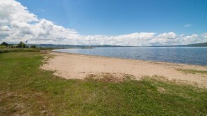 Ein Strand mit einer Rasenfläche und einem Gewässer.