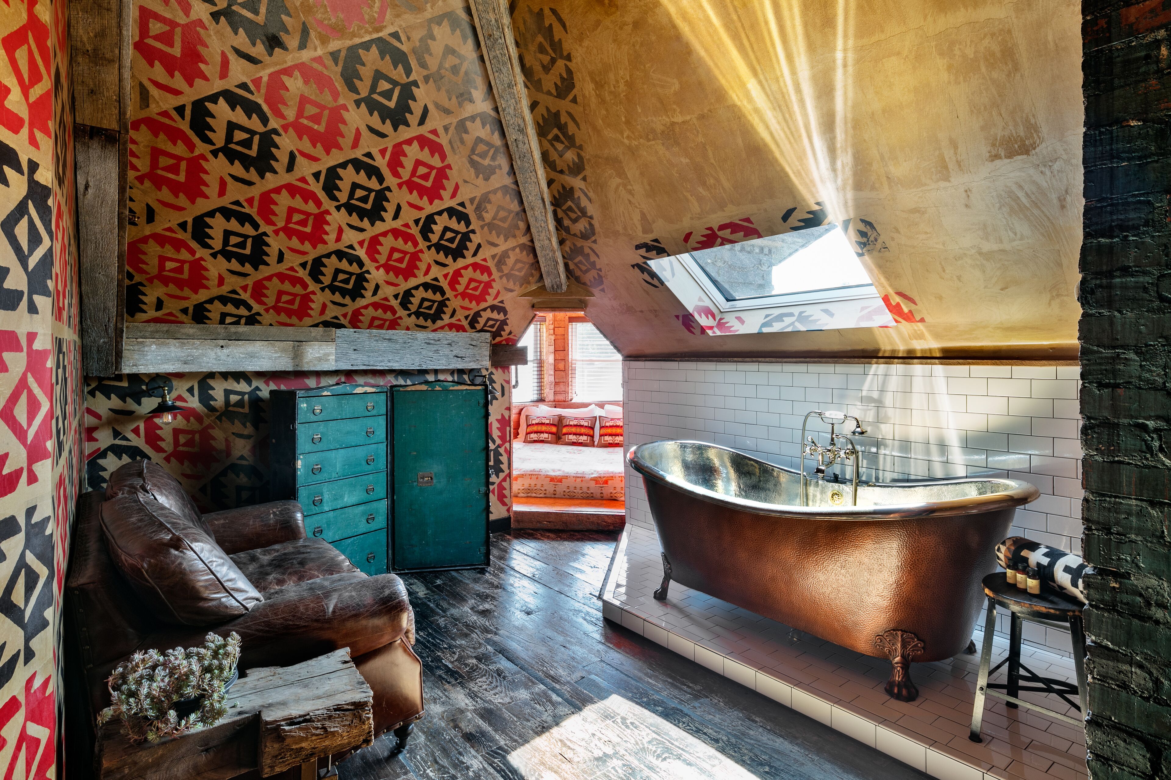 A room with a large bathtub, a wooden bench, and a patterned wall.