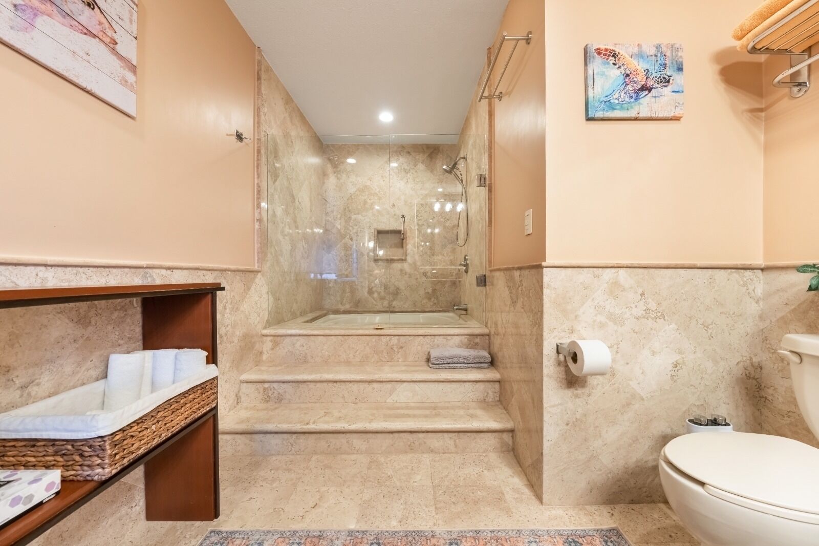 A bathroom with a shower, toilet, and a small shelf with towels.
