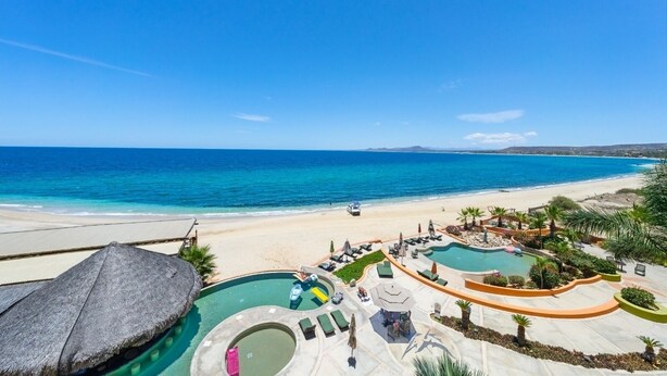 A resort with a pool area, beach, and ocean view.