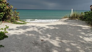 Un sentier de gravier mène à une plage d’où l’on peut admirer l’océan sous un ciel nuageux.
