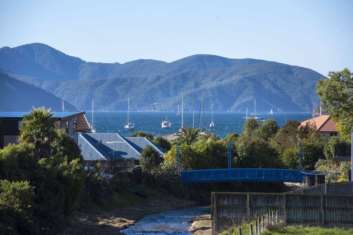 A coastal area with a bridge, boats, and houses with blue roofs.