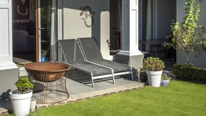 A modern two-story house with a covered patio, outdoor seating, and potted plants. - Wilkes Way Villa (Picton)
