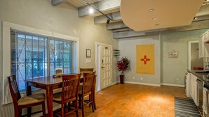 A spacious kitchen with a dining area, featuring a large window with blinds, a wooden dining table with chairs, and a kitchen counter with appliances. - #5: Walk to Old Town Plaza, King & Queen beds, 2 TV's (Albuquerque)