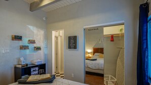A bedroom with a bed, a bookshelf, a wall-mounted sign, and a view into another room. - #5: Walk to Old Town Plaza, King & Queen beds, 2 TV's (Albuquerque)