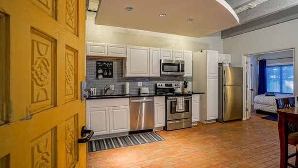 A modern kitchen with white cabinets, stainless steel appliances, and a brick floor. - #5: Walk to Old Town Plaza, King & Queen beds, 2 TV's (Albuquerque)
