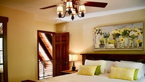 A bedroom with a large bed, a ceiling fan, a wooden door, and a painting of flowers on the wall. - Cabin, hot tub, fire pit, pool, resort access, boating, spa, golf, hiking (Lake Lure)