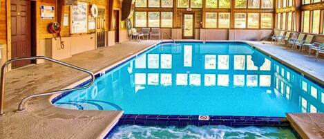 Ein Hallenbad mit Whirlpool-Bereich, Holzvertäfelung und Fenstern.