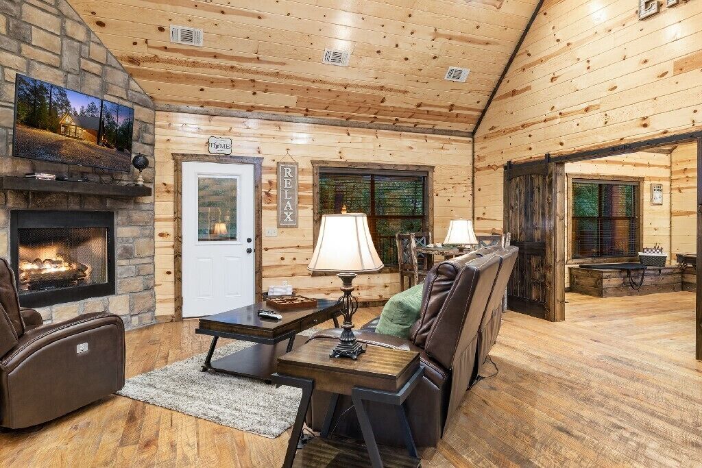 Un intérieur chaleureux de chalet en bois, avec une cheminée, un fauteuil inclinable en cuir et un coin repas.