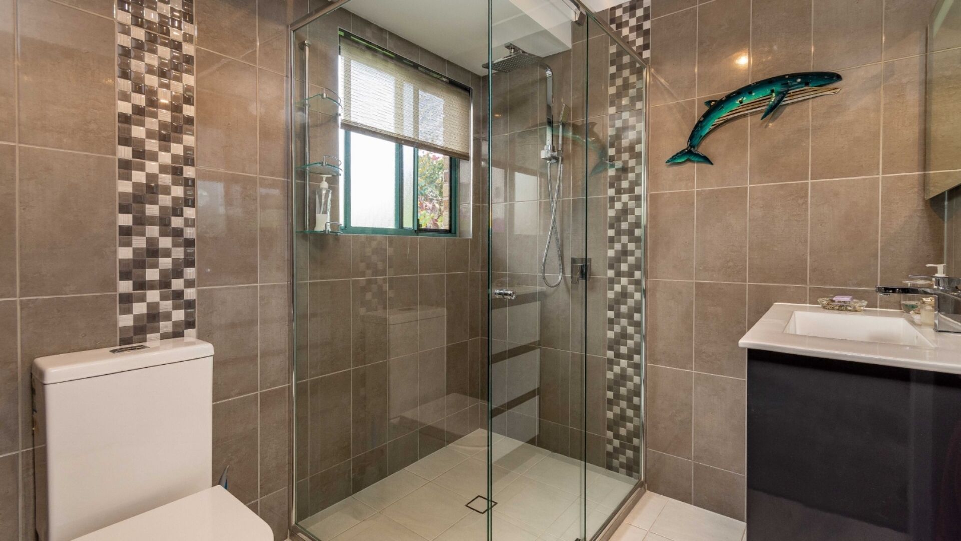 Ein modernes Badezimmer mit einer gläsernen Duschkabine, einer backsplash mit Schachbrettmuster und einer großen Fischdekoration.