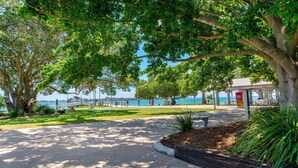 A park with a paved walkway, trees, and a view of the sea. - Delightful Duplex on Rose (BONGAREE)