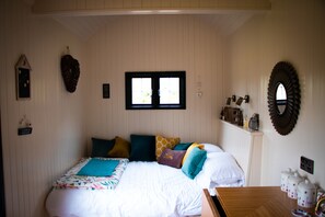 Un dormitorio con cama, almohadas, una ventana, un reloj de pared y un espejo.
