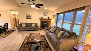 Ein Wohnzimmer mit Sofa, Couchtisch, Kamin und großem Fenster.
