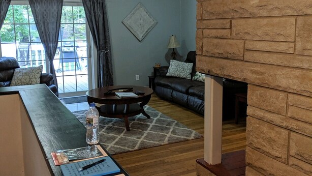 A living room with a stone fireplace, a sofa, a coffee table, and a dining table. - CHARMING NEIGHBORHOOD IN PURDUE'S BACKYARD (West Lafayette)