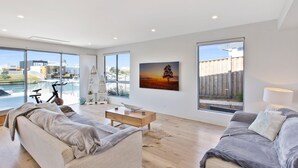 A modern living room with a large window, a sofa, a coffee table, and a bike in the background.