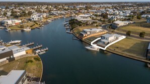 An aerial view of a marina with boats docked, surrounded by residential buildings and a small island with a house.