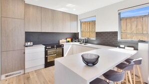 A modern kitchen with a central island, bar stools, and a large window.