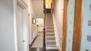 A narrow hallway with a carpeted staircase leading to a door.