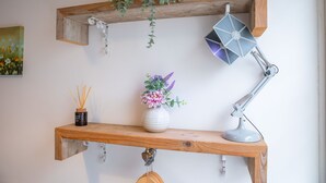 A wooden shelf with a white vase of flowers, a desk lamp, and a small container of incense sticks.