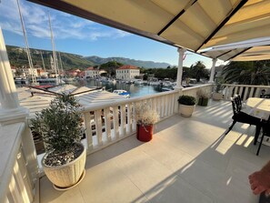 A balcony with potted plants, a table, and chairs. - Panoramic Sea View Villa-Pool & BBQ – Seafront Villa in the Heart of Jelsa, Hvar (Jelsa)