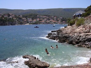 A coastal area with rocky terrain and a clear view of a town in the background. - Panoramic Sea View Villa-Pool & BBQ – Seafront Villa in the Heart of Jelsa, Hvar (Jelsa)