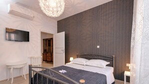 Een slaapkamer met een bed, een televisie, een bureau en een kledingkast.