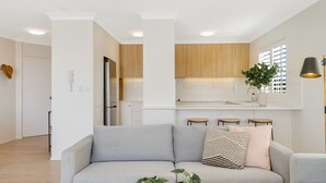 A modern kitchen with wooden cabinets, a built-in oven, and a large window. - Beach Pines 5 - Fully Renovated North Kirra Beachfront - Min. 3 Night Stays (Bilinga)