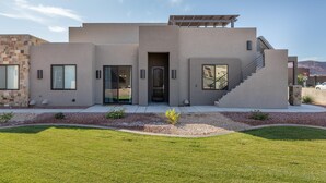 A modern house with a flat roof, a covered front porch, and a staircase leading to the entrance.