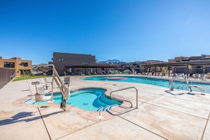 A pool area with multiple swimming pools, a covered seating area, and a view of surrounding buildings. - Epic Escape (St. George)