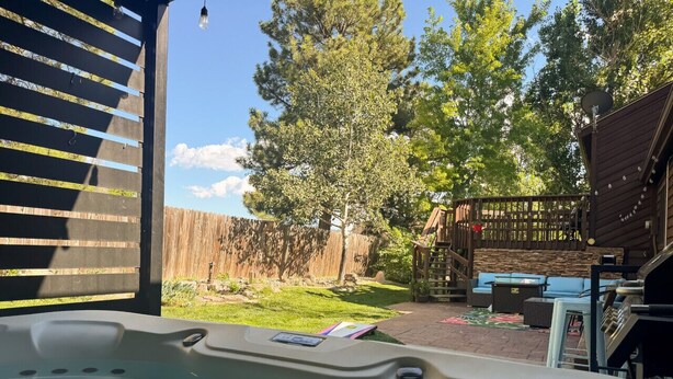 A hot tub with a view of a backyard patio area, including outdoor furniture and a wooden deck. - Theater Room | Hot Tub | Arcades | Great Location! (Spearfish)