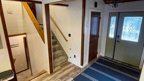 A staircase leading to a door with a doormat, a wooden floor, and a blue rug. - Theater Room | Hot Tub | Arcades | Great Location! (Spearfish)