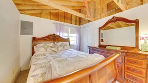 A bedroom with a wooden ceiling, a bed with a patterned bedspread, a dresser with drawers, and a mirror. - Rustic Retreat Across from Lake; Family Friendly! (Union)