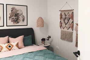 A bedroom with a bed, pillows, a wall hanging, and a hanging light fixture. - Joy Apartment 2 (Lorne)