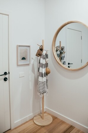 A hallway with a coat rack, a mirror, a framed picture, and a door.
