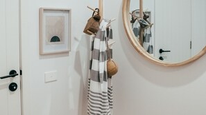 Simple, functional space with a framed picture, woven bag, and round mirror.