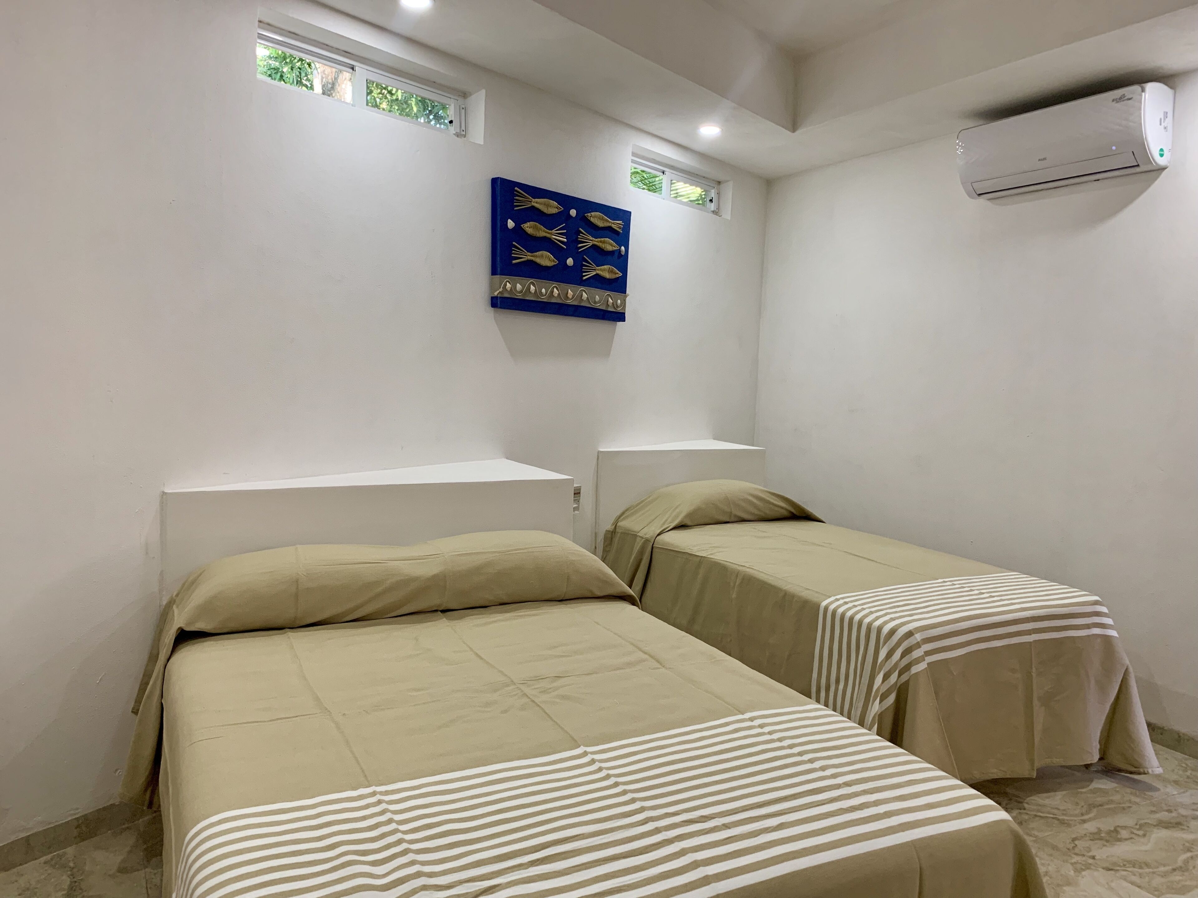 Een kleine, schone kamer met twee eenpersoonsbedden, een raam met uitzicht en een airconditioning.