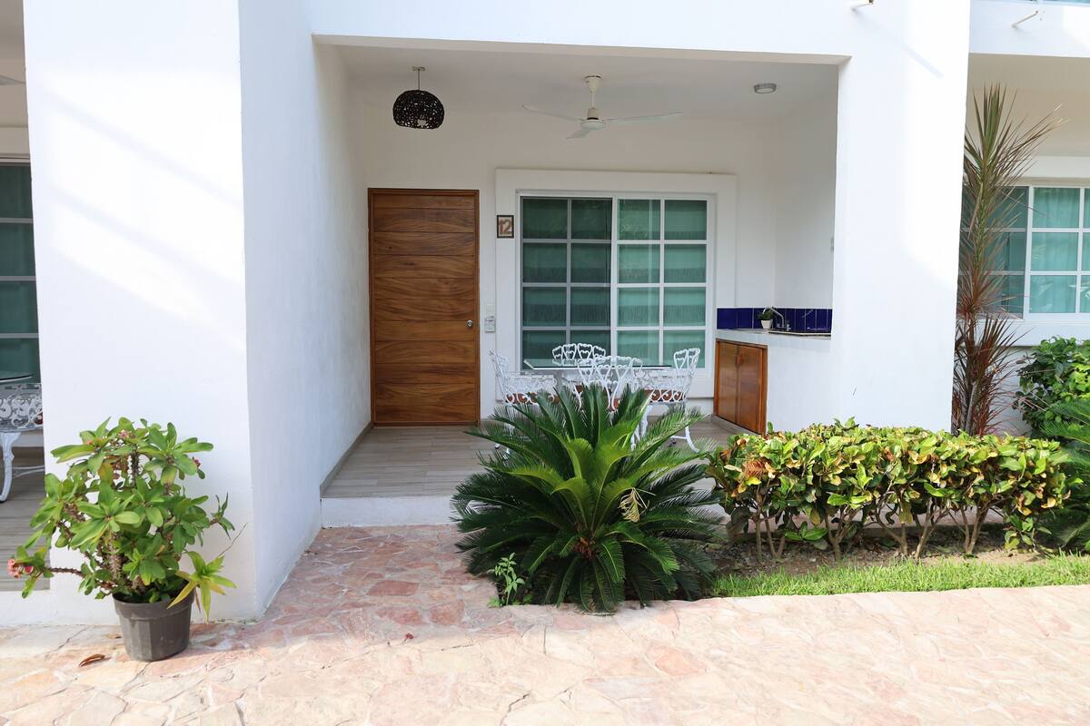 Una entrada de edificio moderna con puerta de madera, un ventanal grande y un pequeño balcón.