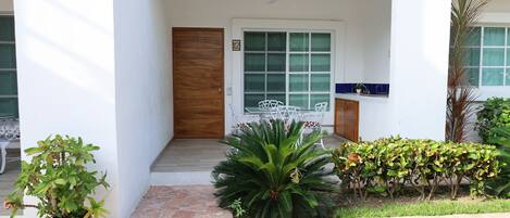 A modern building entrance with a wooden door, a large window, and a small balcony.