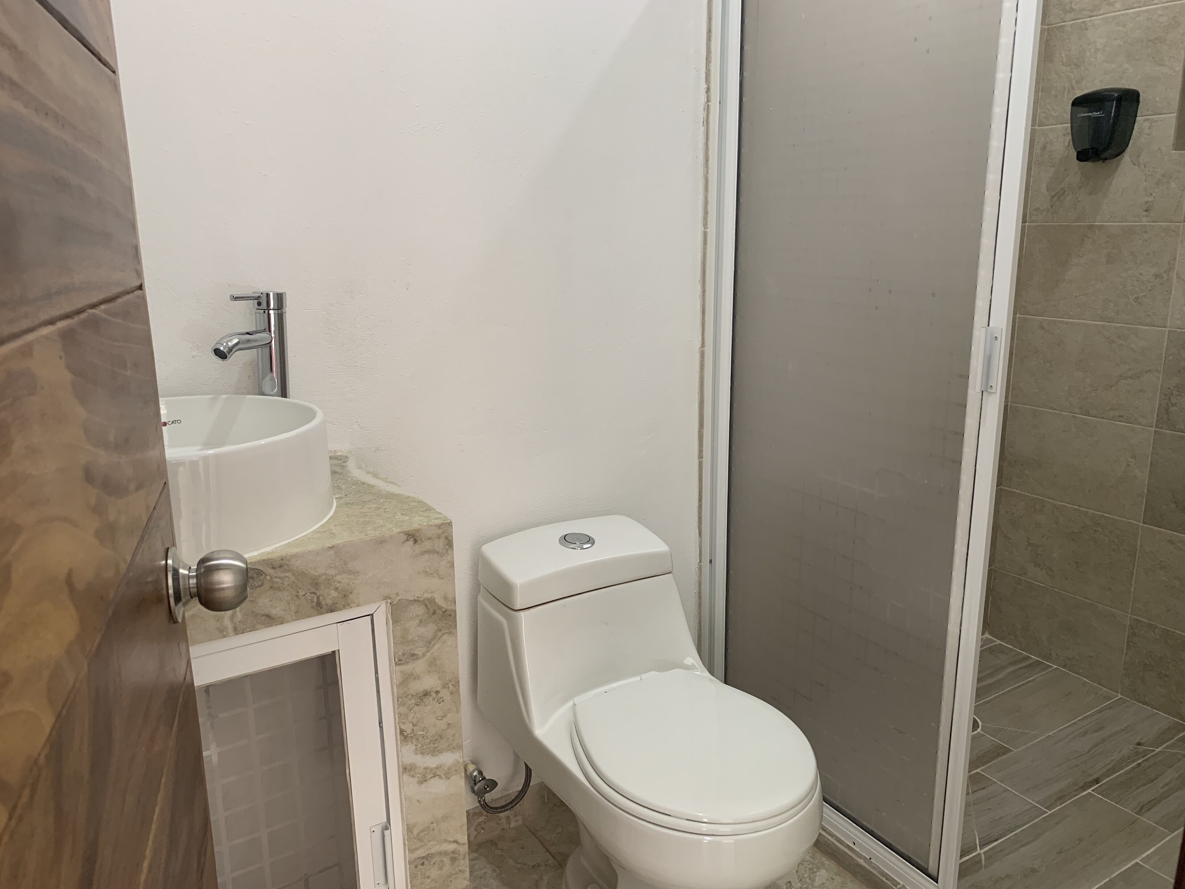 A bathroom with a toilet, sink, and shower area.