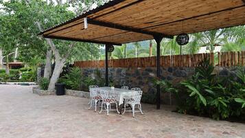 An outdoor patio with stone flooring, white metal chairs, and a table.
