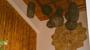 Un escalier avec un mur en pierre, une rampe en bambou et des guirlandes lumineuses décoratives suspendues.