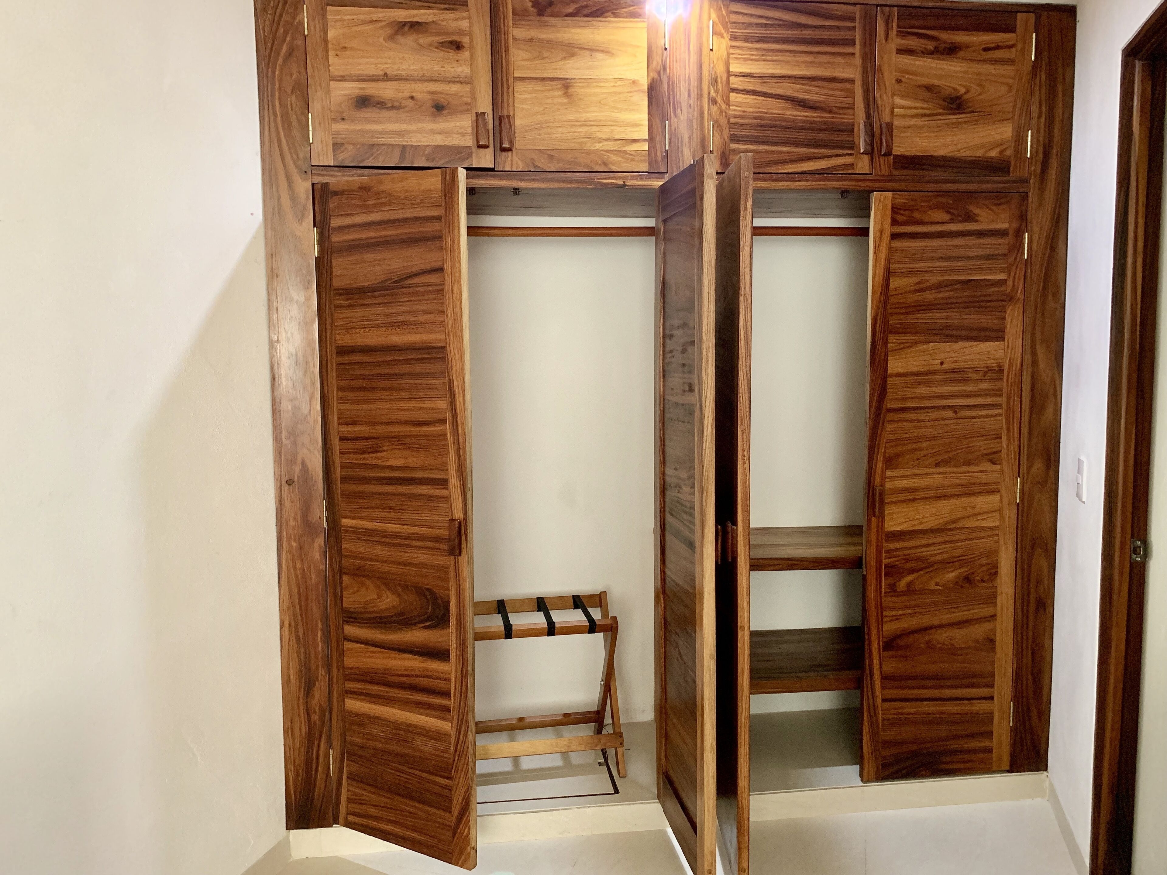 Un placard en bois doté de plusieurs compartiments et d’une petite chaise.