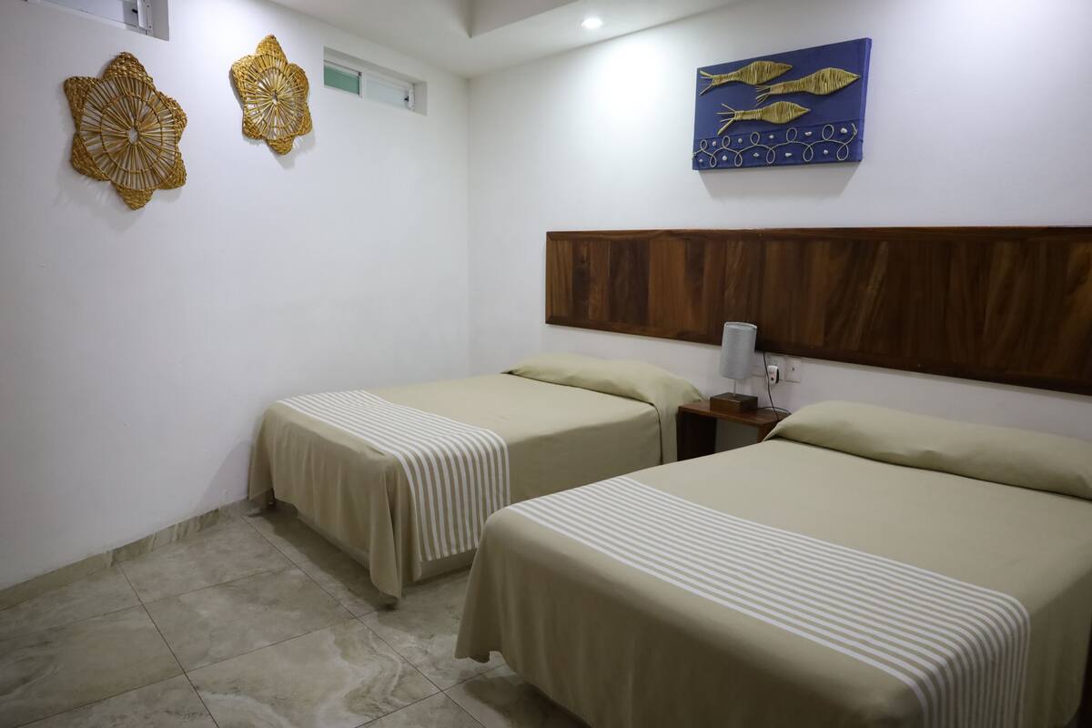 Habitación de hotel con dos camas individuales, cabecero de madera, una obra de arte colgada en la pared y adornos decorativos.