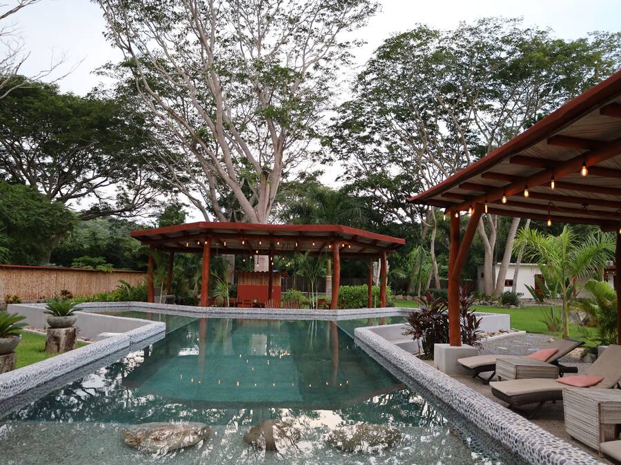 Una piscina con sillas de descanso y un pabellón.