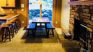 Un interior acogedor con chimenea de piedra, una mesa de comedor de madera y una zona de cocina con armarios de madera.