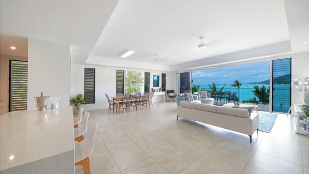 A spacious living area with a large window offering a view of the ocean. - Luxury 4 bedroom, 4 bathroom apartment in Central Airlie with the best views (Airlie Beach)