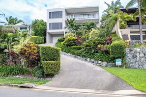 A modern building with a paved driveway leading to a gated entrance.