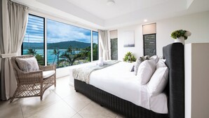 A bedroom with a large window, a bed, a chair, and a view of the ocean. - Luxury 4 bedroom, 4 bathroom apartment in Central Airlie with the best views (Airlie Beach)