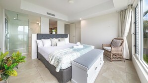 Een moderne slaapkamer met een groot bed, een nachtkastje, een stoel en uitzicht op de omgeving.